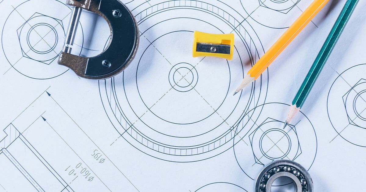 Tool blueprints with caliper, pencils, and sharpener on paper.